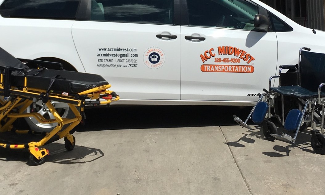 Electric stretcher and wheelchair beside an ACC Midwest van